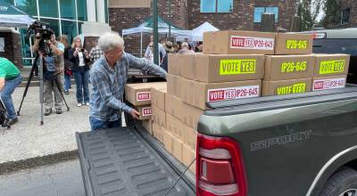 A volunteer for Lets Go Washington unloads boxes of petitions for Initiative 645 that were turned in to the secretary of states office on July 2, 2026. The measure seeks to repeal the states new income tax on high earners. Differences on how to describe the fiscal effects of the measure passing has sparked legal fights that could reach the state Supreme Court. (Photo by Jerry Cornfield / Washington State Standard)